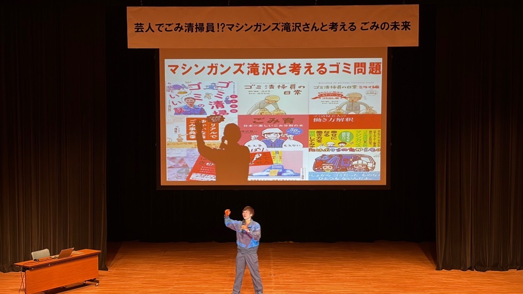 壇上でスピーチ中のマシンガンズ滝沢さんの写真