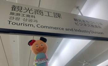 観光商工課の看板と「マイ」のぬいぐるみの写真