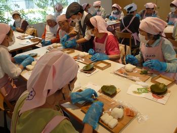 参加者が揃って柿の葉寿司を作っている写真