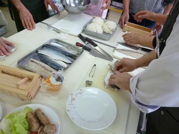 参加者が鯖の下ごしらえをしている写真