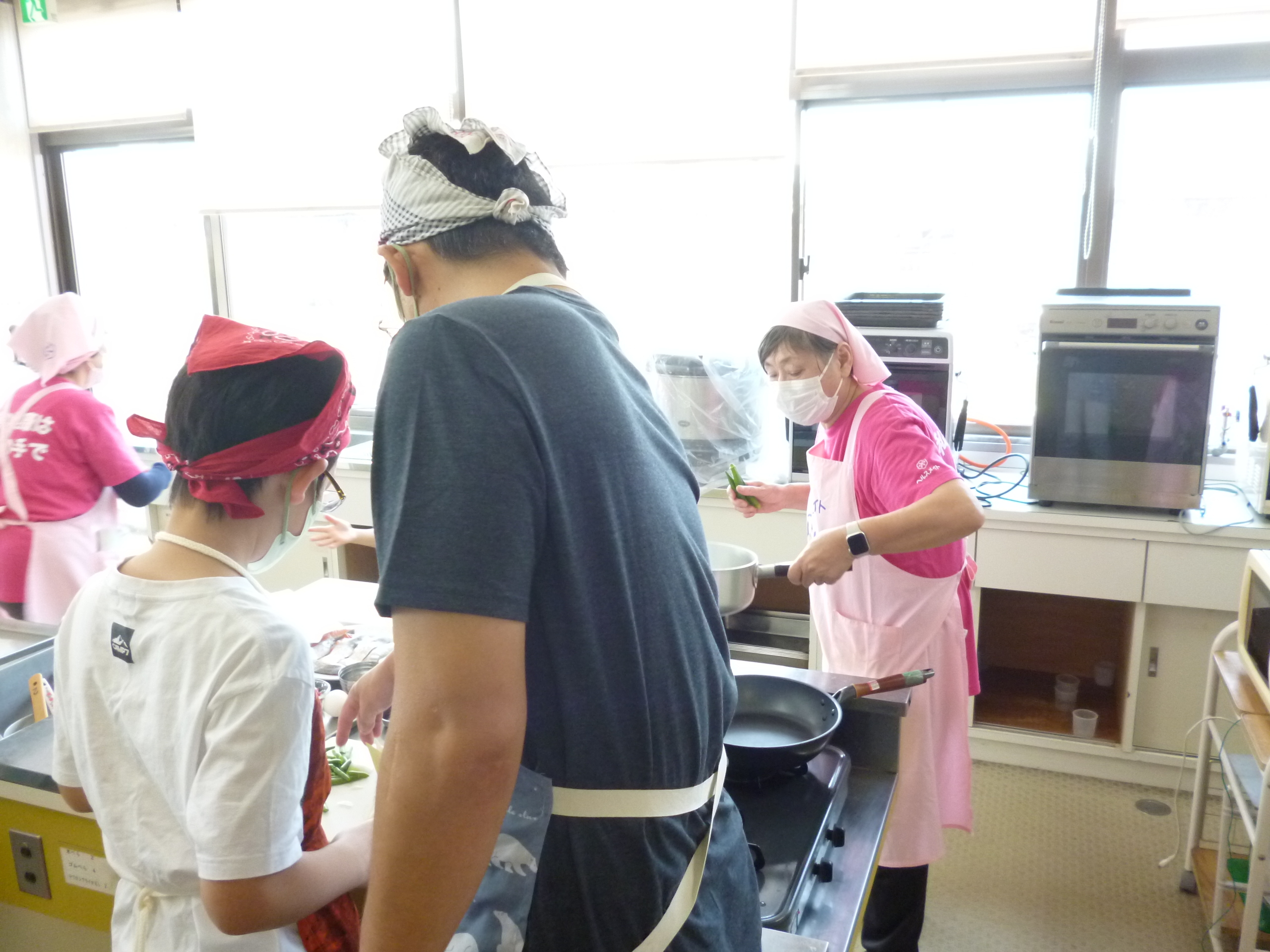 子どもが父親に教えてもらいながら包丁を使っている様子