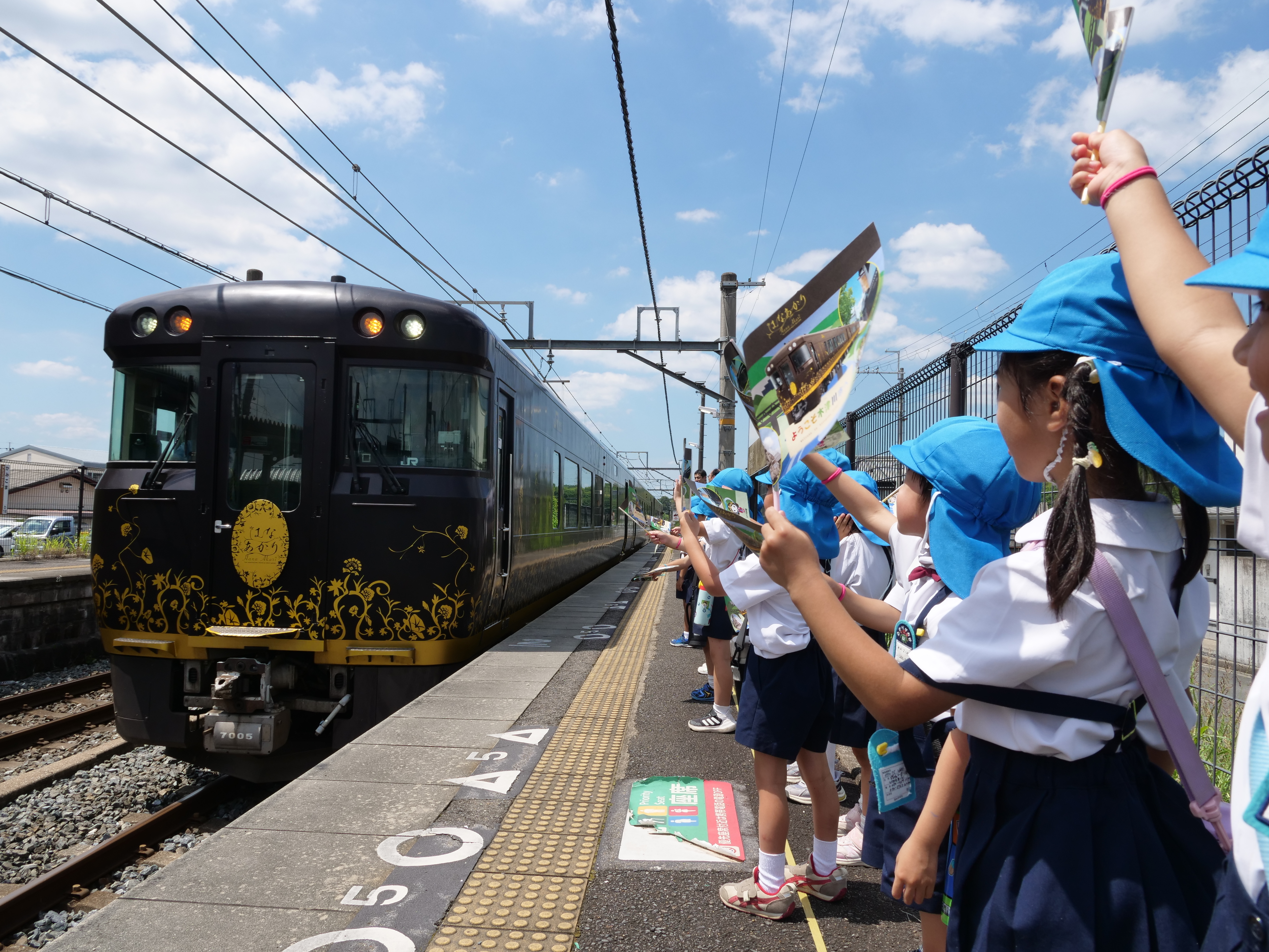幼稚園児が観光列車はなあかりを出迎えている様子